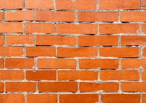 Texture of a red brick wall with lines of cement joints. Stock Photos