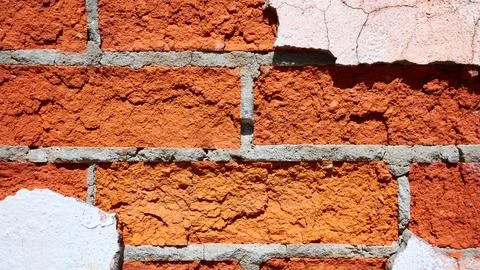 Texture of a red brick wall with pieces of peeled off plaster Stock Photos