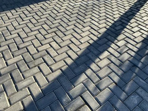 Texture of road tiles with herringbone pattern. Pavement tiled floor. Stone.. Stock Photos