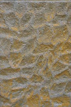 Texture of a rough stone wall with a yellow hue and irregular patterns Stock Photos