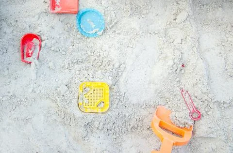 The texture of the sand on the beach. Bright plastic toys lie in the sand. Stock Photos