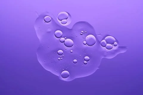 The texture of the serum on a purple background. Stock Photos