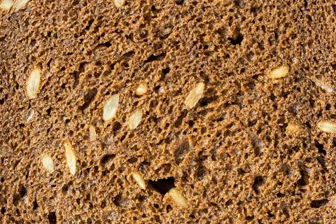 The texture of a slice of black rye bread with seeds. Stock Photos