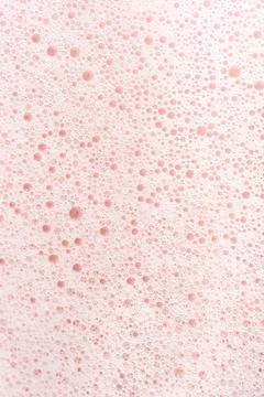 The texture of soap foam with bubbles on a pink background. Stock Photos
