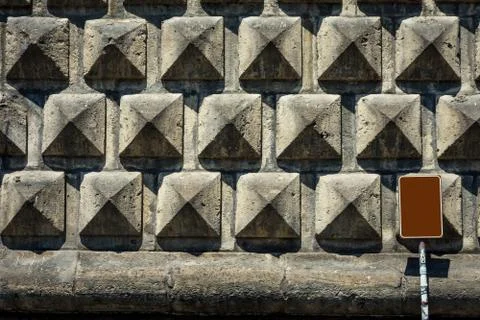 Texture of a stone brick wall in sunlight, close-up with metal plate. Stock Photos