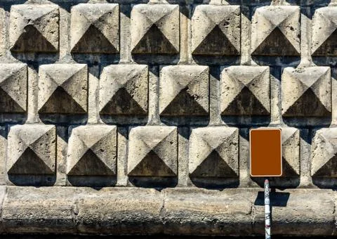 Texture of a stone brick wall in sunlight, close-up with metal plate. Stock Photos