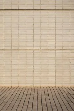 Texture of a stone wall with beige bricks at the street in the morning. Pattern 库存照片