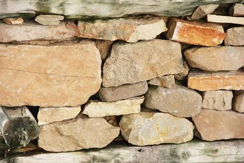 The texture of  stone wall made of brown stones and old moldy wood Stock Photos