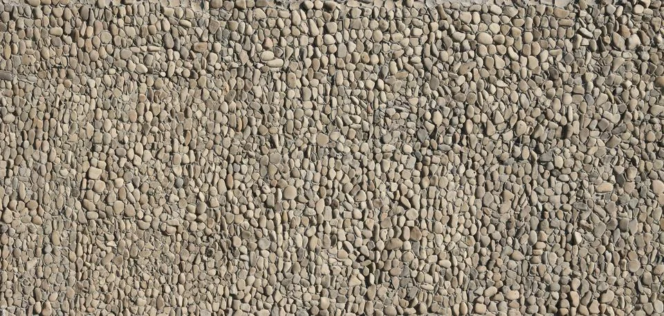 Texture of a stone wall with small round pebble stones. Part of a stone wall  Stock Photos