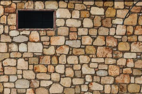 Texture of a stone wall with a small window. Background texture of the stone  Foto stock