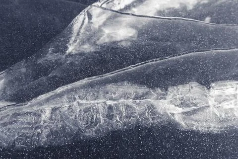 Texture of stripes and cracks on a thick layer of ice of a lake or river. whi Stock Photos