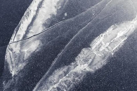 Texture of stripes and cracks on a thick layer of ice of a lake or river. whi Stock Photos