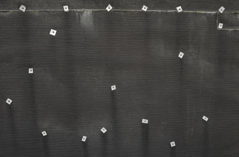 Texture of a surface of a construction ruberoid close-up pierced by nails Stock Photos