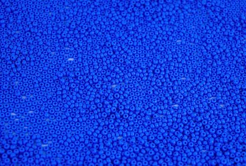 The texture of the surface of scattered blue beads for needlework. Stock Photos
