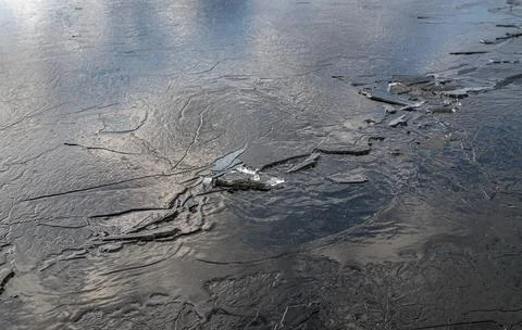 The texture of thin melting ice on a spring lake with the sky reflected on th Foto stock