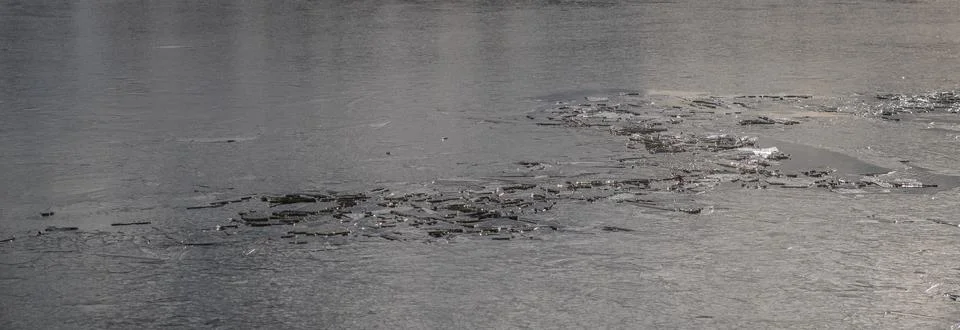 The texture of thin melting ice on a spring lake with the sky reflected on th Foto stock