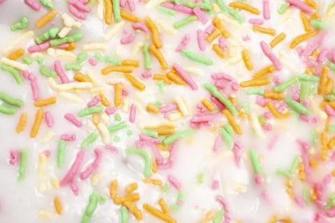 Texture of the Traditional Easter cake with white icing and colorful sprinkle 库存照片