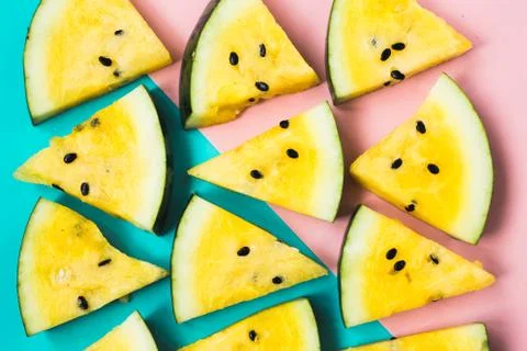 Texture of triangular slices of ripe yellow watermelon on blue-pink backgroun 写真素材