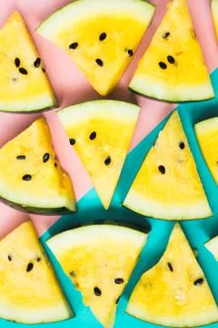 Texture of triangular slices of ripe yellow watermelon on blue-pink backgroun 스톡 사진