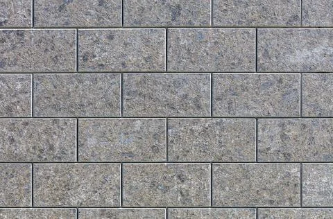 The texture of the wall is lined with polished stone tiles, illuminated by su 스톡 사진