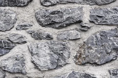 Texture of the wall is made of clay and rough gray marble stones as a background Stock Photos