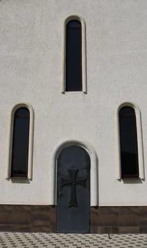 Texture wall of the temple with narrow windows and door with a cross Stock Photos