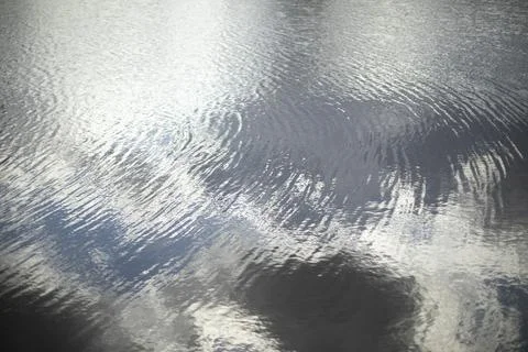 Texture of water. Reflection of clouds in water. Ripples on lake. Stock Photos