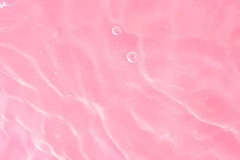 Texture of waves of bubbling water on a pink background Stock Photos