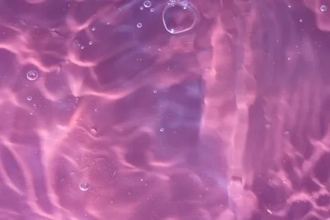 Texture of waves of bubbling water on a pink background Stock Photos