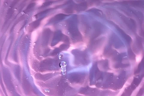 Texture of waves of bubbling water on a pink background Stock Photos