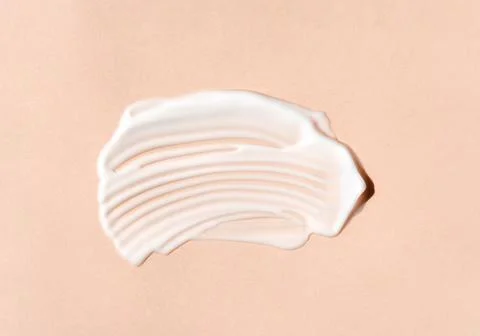 Texture of white cream on beige background. Smear of moisturizer closeup. Stock Photos