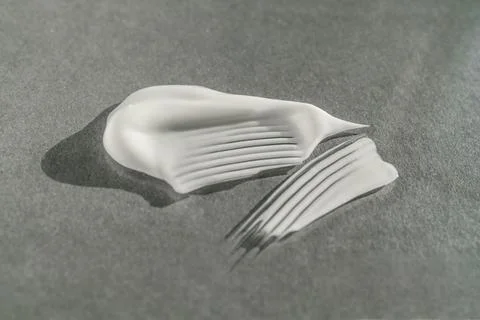 The texture of the white cream on a gray background. Stock Photos