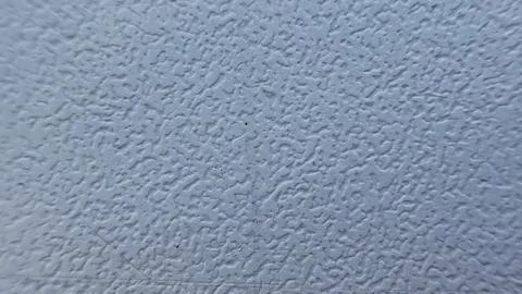Texture of white embossed plastic or plaster with fine grainy relief close-up. Stock Photos