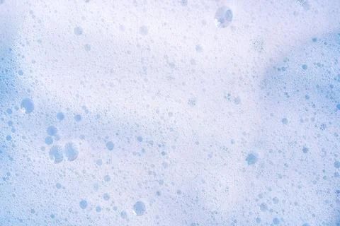 Texture of white foam on blue backdrop. Foam cosmetic product for selfcare Stock Photos