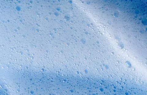 Texture of white foam on blue background. Foam cosmetic product for skincare Stock Photos