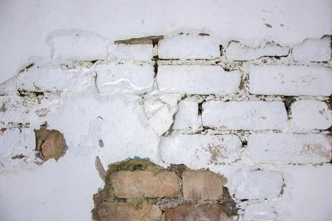Texture white wall shows cracks and patches with exposed bricks in building 스톡 사진
