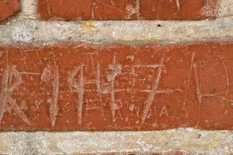 Texture, writing and scratch on brick wall of building in city for background Fotos de archivo