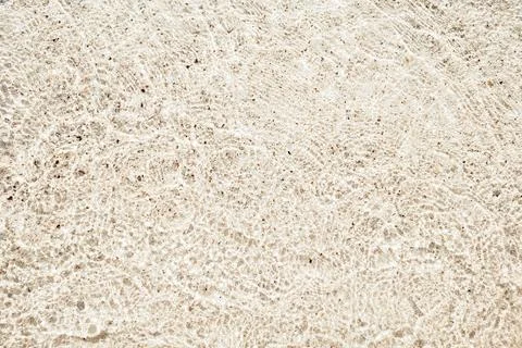 Texture of yellow sand, pebbles and clear water. Beautiful beach background.. Stock Photos