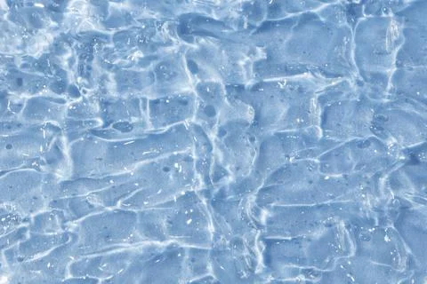 Textured backdrop of turquoise colored clear rippling water surface on beach Stock Photos