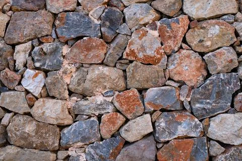 Textured background of stone wall made of natural multicolored stones. Stock Photos