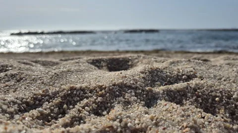 Textured beach sand with distant sea and rocks blurred in the background. Video stock 315008679