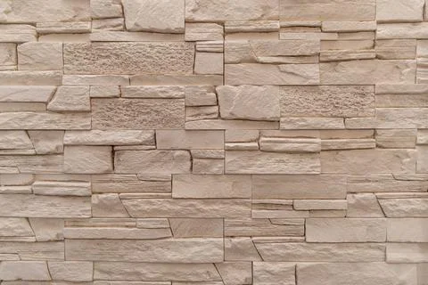 Textured beige stone wall with interlocking brick pattern Stock Photos
