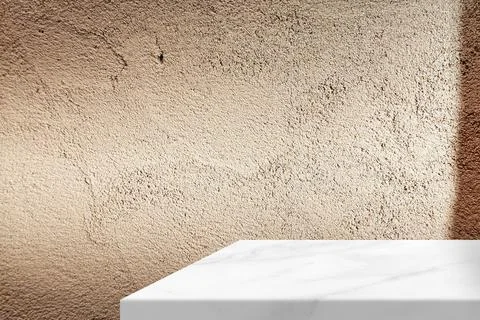 Textured beige stucco wall background with white marble table and shadow Stock Photos