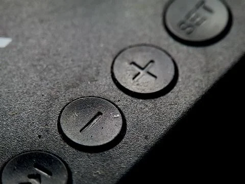 Textured black surface features round buttons with imprinted shapes, in dar.. Stock Photos