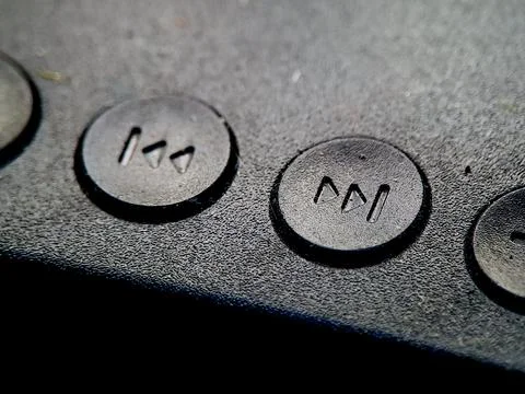 Textured black surface showcasing round buttons with symbol for rewind or f.. Stockfoto's