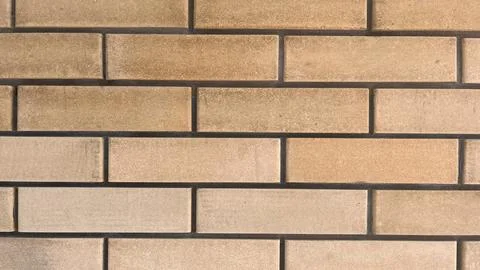 Textured brick wall showcasing a warm beige color pattern with uniform rect.. Stock Photos