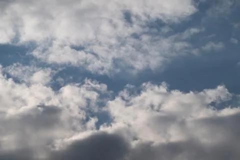 Textured clouds framing open sky patches, subtle shadow play, gentle blues an Stockfoto's