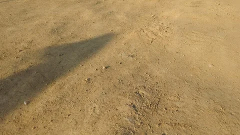 A textured dirt path with clear shadows cast across its surface. The ground.. Video stock 322557588