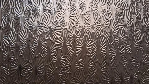 Textured glass surface featuring repeating star and fan shaped patterns Stock Photos
