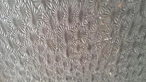 Textured glass surface featuring repeating starburst patterns in natural light 스톡 사진